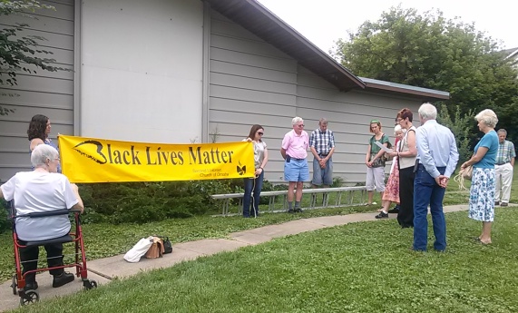 Group gathered with Black Lives Matter banner unfurled, about to be hung on exterior wall of Second Unitarian Church.
