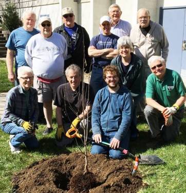 Participants of church clean-up day gather around a tree they have planted