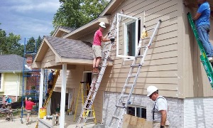 Workers finishing siding on front of home