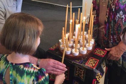 Child lighting a candle or joy or concern