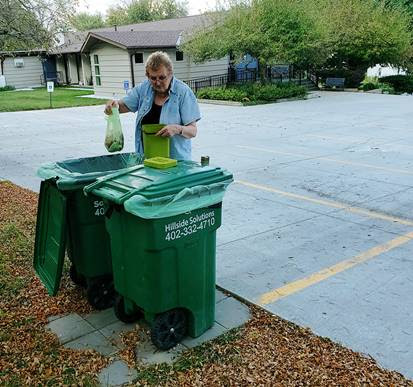 Woman dropping her organic household waste into Hillside Solutions bins.