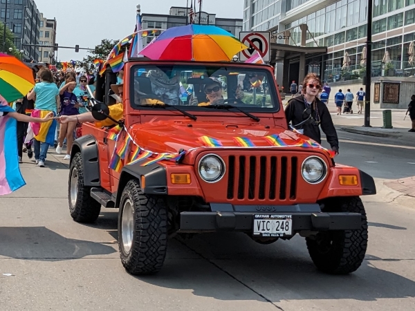 Red Jeep with Pride banners and umbrella.