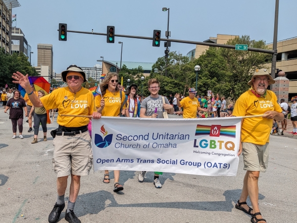 Two members carrying the Second Unitarian Church banner in Pride parade.