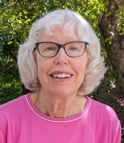 Vicki Pratt - White hair, glasses, pink knit shirt.